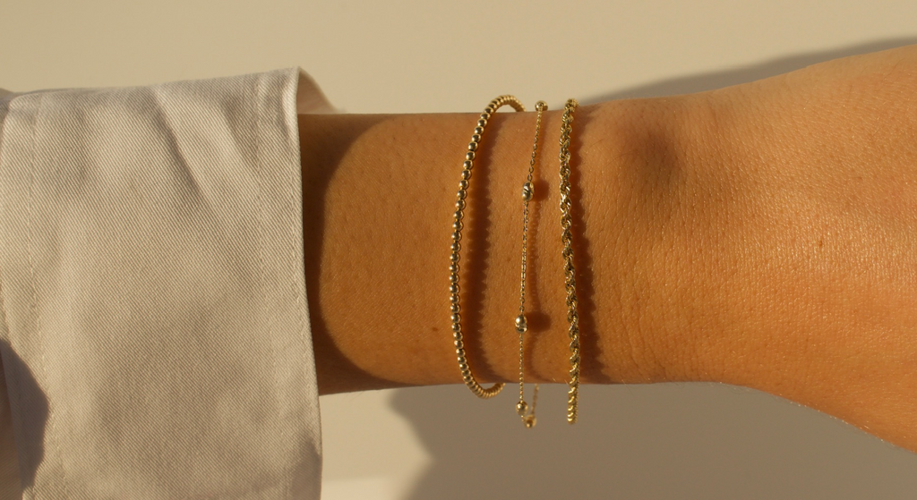 Woman's wrist with 3 FJC bracelets in golden sunlight